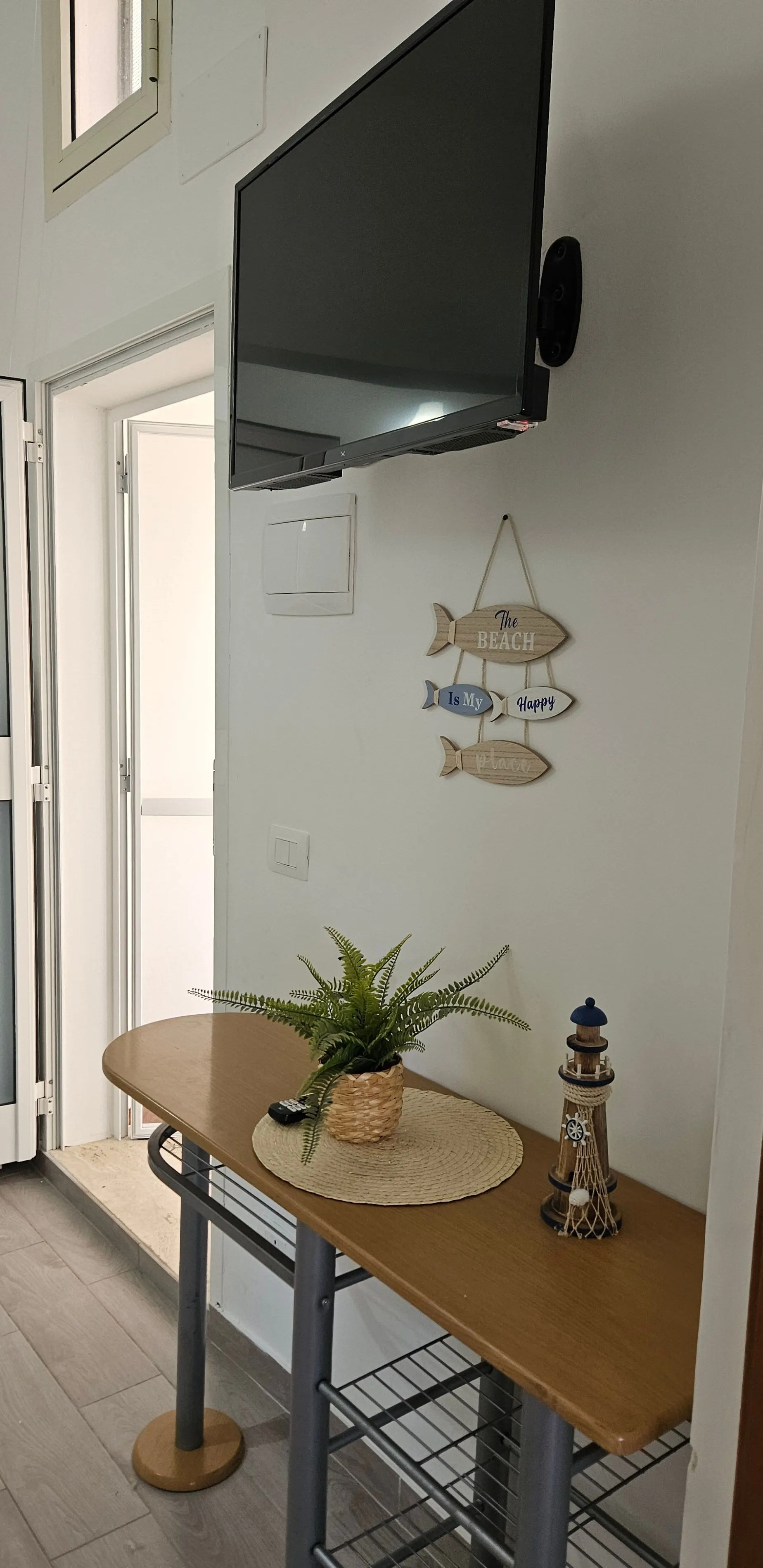 Dettagli marini: pesci decorativi alla parete e piccola pianta su un sottopiatto in corda.