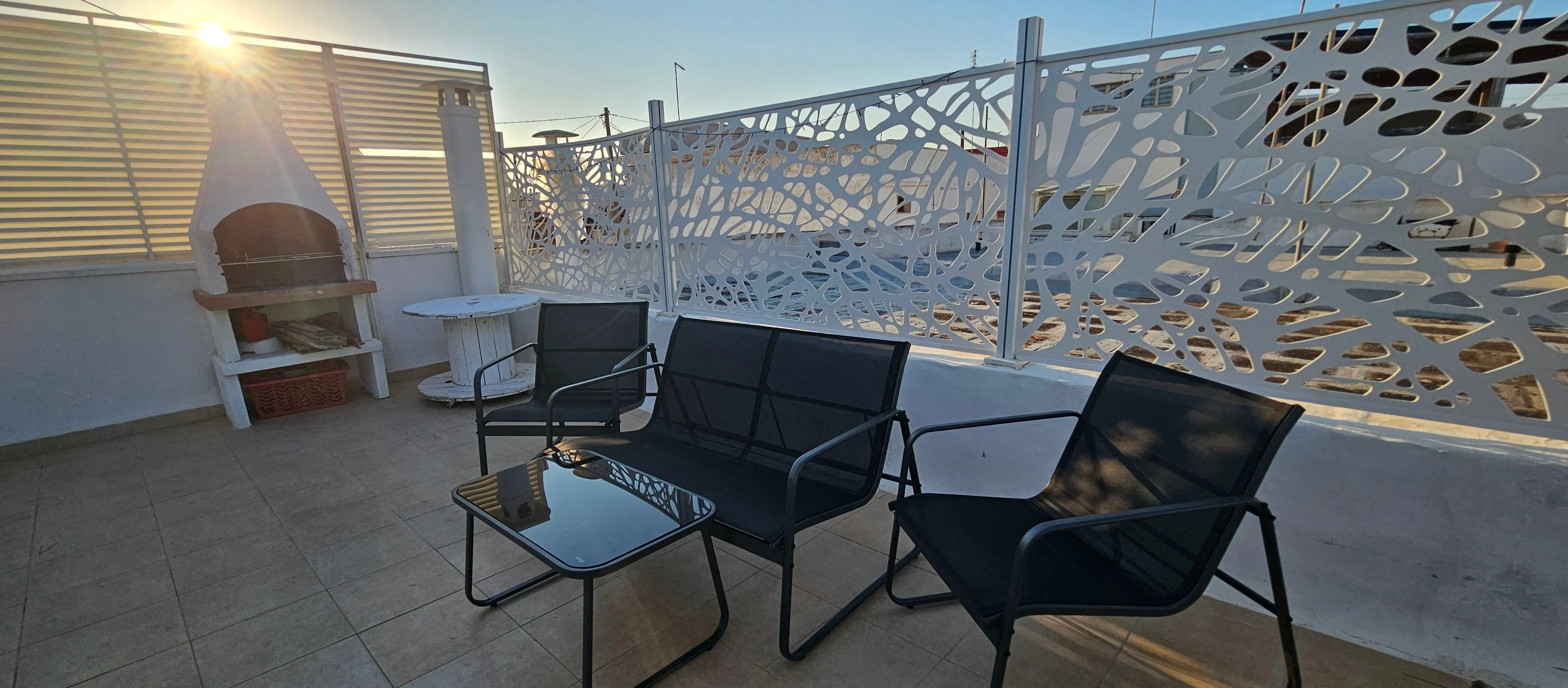 Terrazza al tramonto, divanetti relax in primo piano e luce calda controluce.